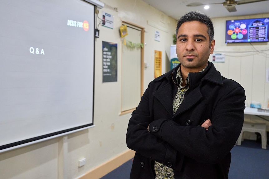 A man with his arms crossed in a classroom