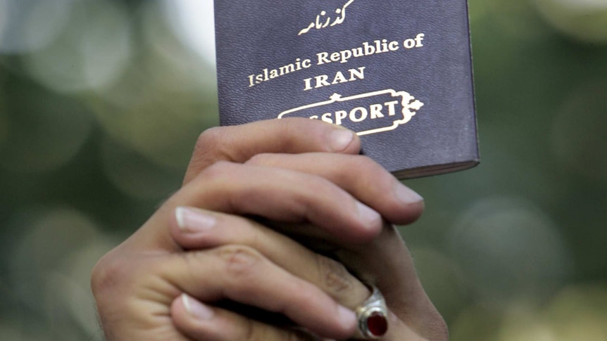 An Iranian passport is held in the air.