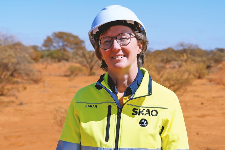 Photo of  a woman with hard hat and high-vis clothes smiling on country.