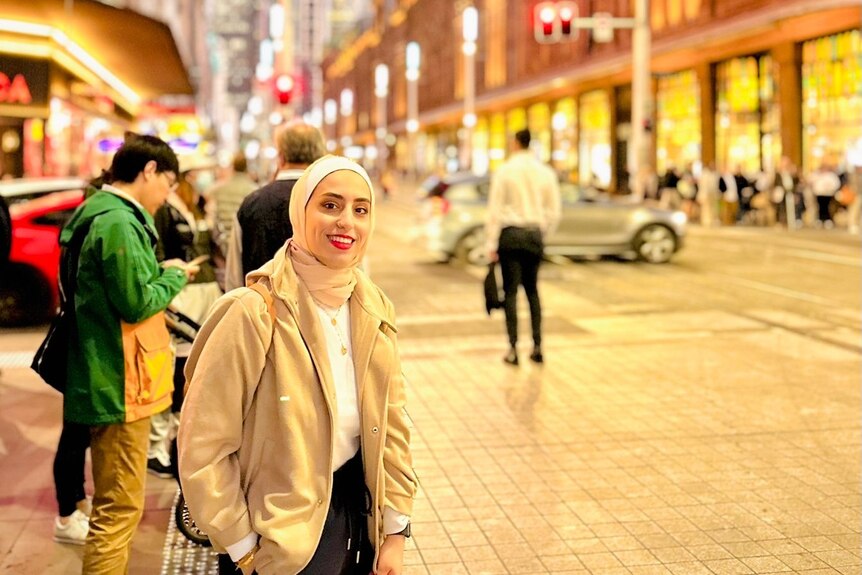 a woman poses for a photo in the street.