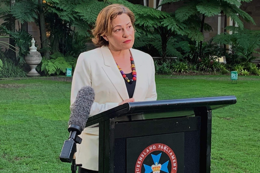 Jackie Trad standing at a podium with microphones attached on the lawn on the parliament green
