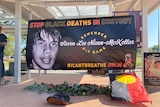 A banner bearing the face of a young Indigenous man who died in custody.