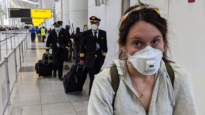 Ed Coper's wife wearing a mask, in front of several pilots in masks, at JFK