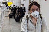 Ed Coper's wife wearing a mask, in front of several pilots in masks, at JFK