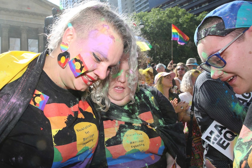 Indigenous supporters of the Yes vote are covered in coloured powder as they wear rainbow coloured attire at a gathering