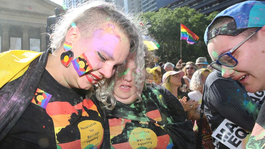 Indigenous supporters of the Yes vote are covered in coloured powder as they wear rainbow coloured attire at a gathering