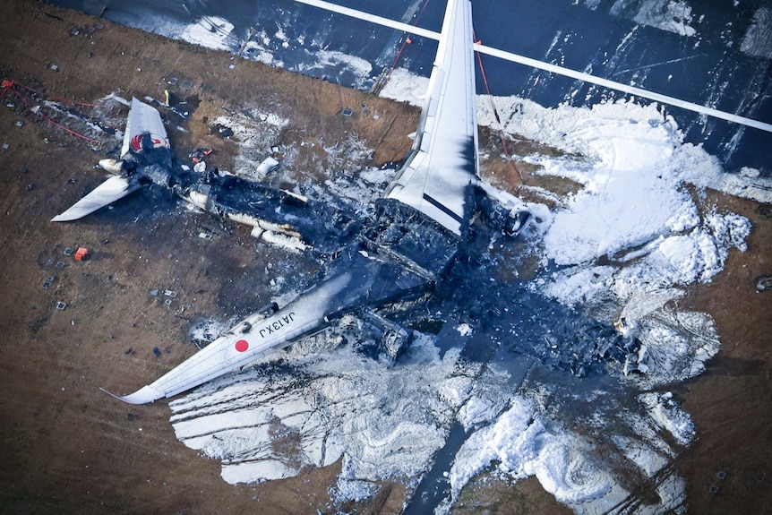 A burned out plane on a runway 