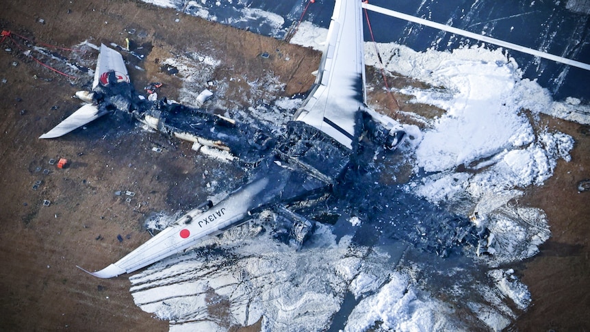 A burned out plane on a runway 