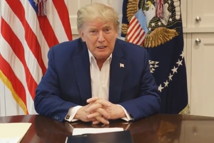 Donald Trump sitting at a desk, facing the camera.