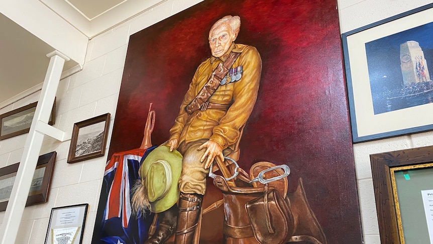 A large portrait of an older man in a soldier's uniform hanging on a wall. 