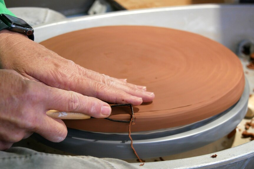 hands on a pot being made on a wheel