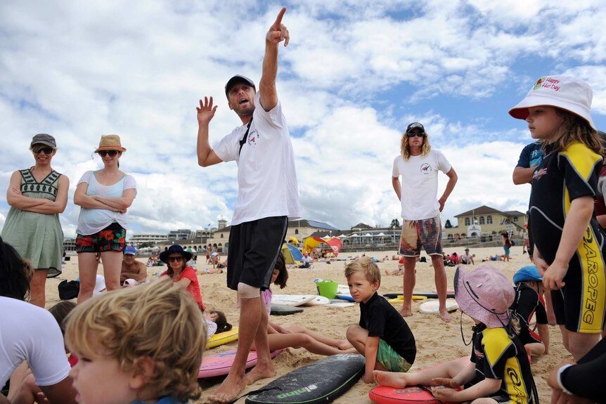 Surfsquad instructor Barney Quinlan with Little Heroes families on Bondi Beach