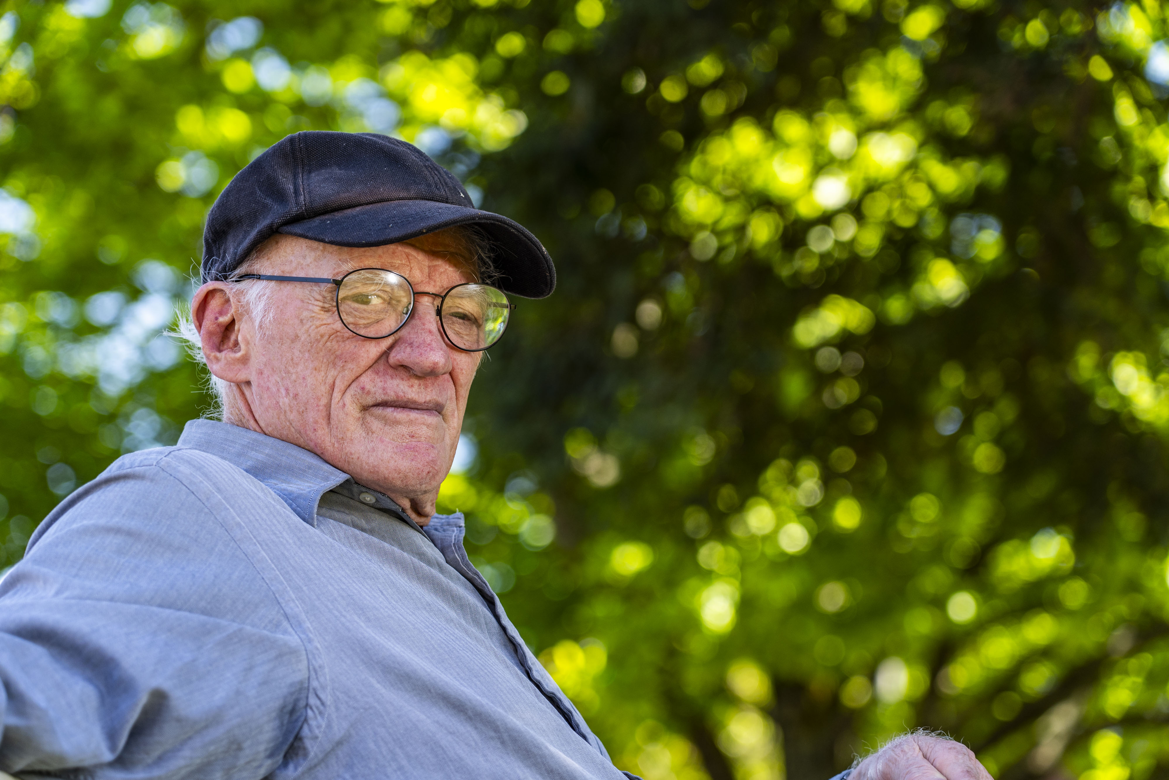 A man with a hat and glasses looks at the camera.