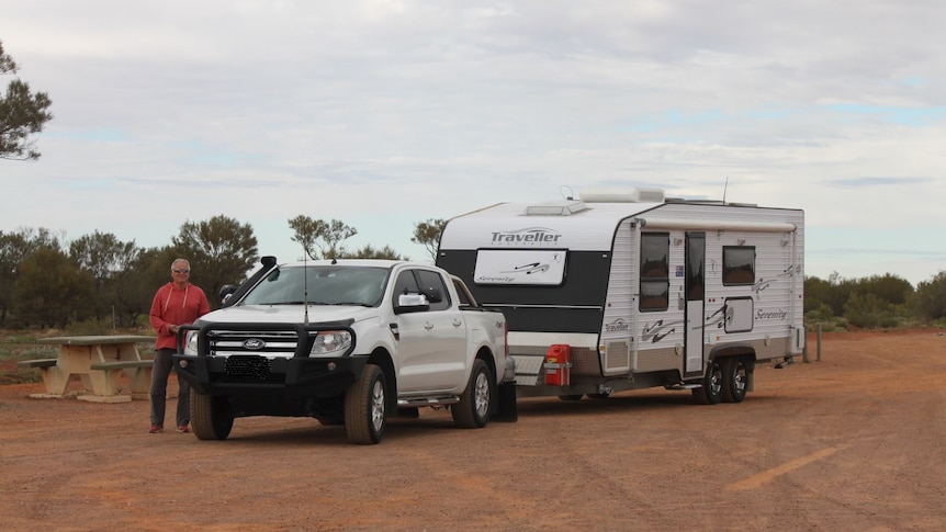 Vlad Chudoschnick leans against his ute, with caravan behind. 