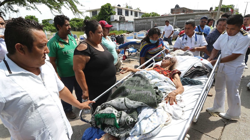 Evacuated patients lie in beds outside after their hospital was damaged by earthquake.