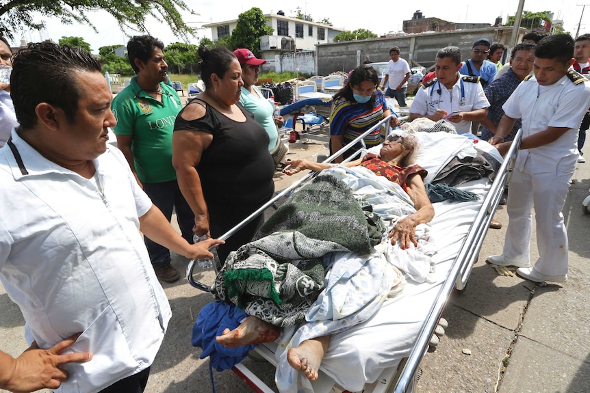 Evacuated patients lie in beds outside after their hospital was damaged by earthquake.