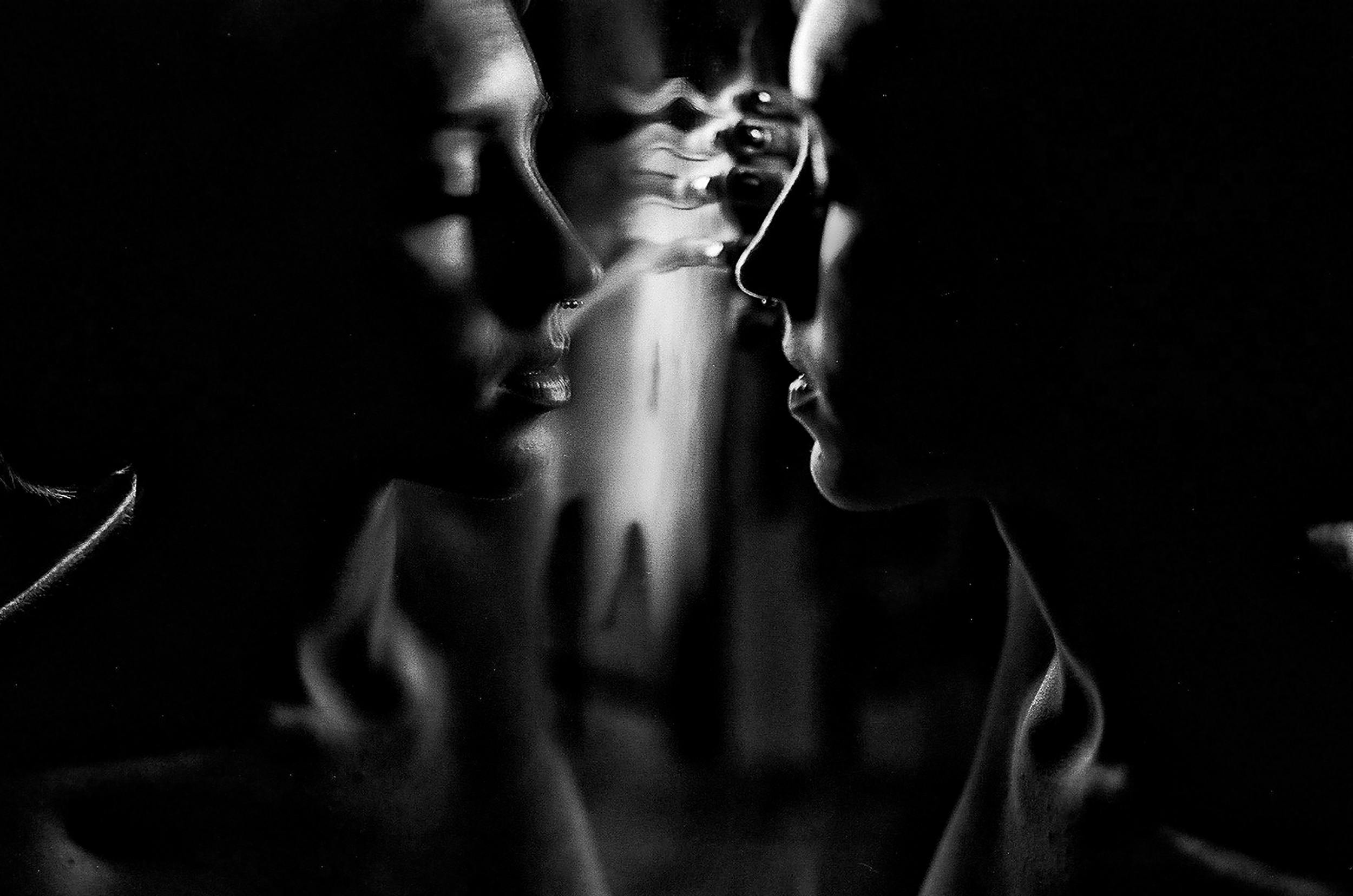 Dreamy woman with eyes closed touching glass, in black and white.