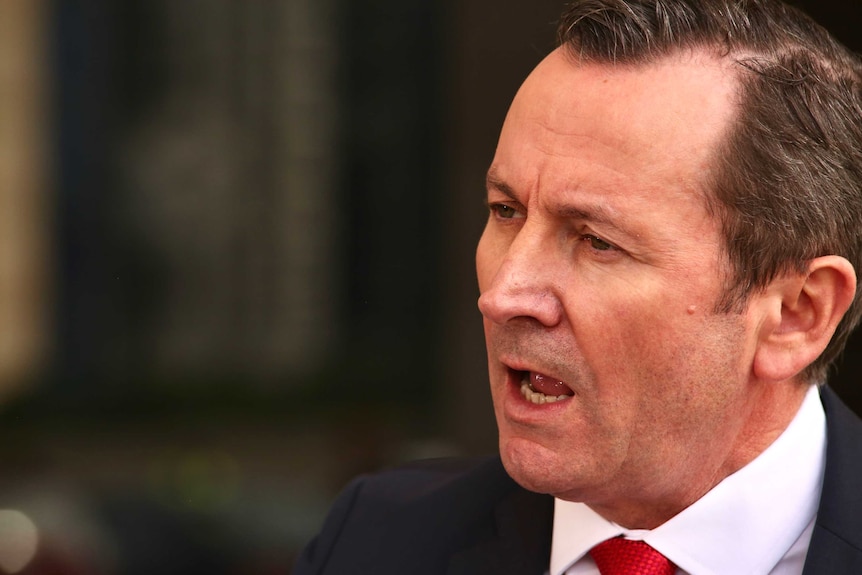 WA Premier Mark McGowan speaks outside parliament in West Perth, wearing a red tie and black suit.