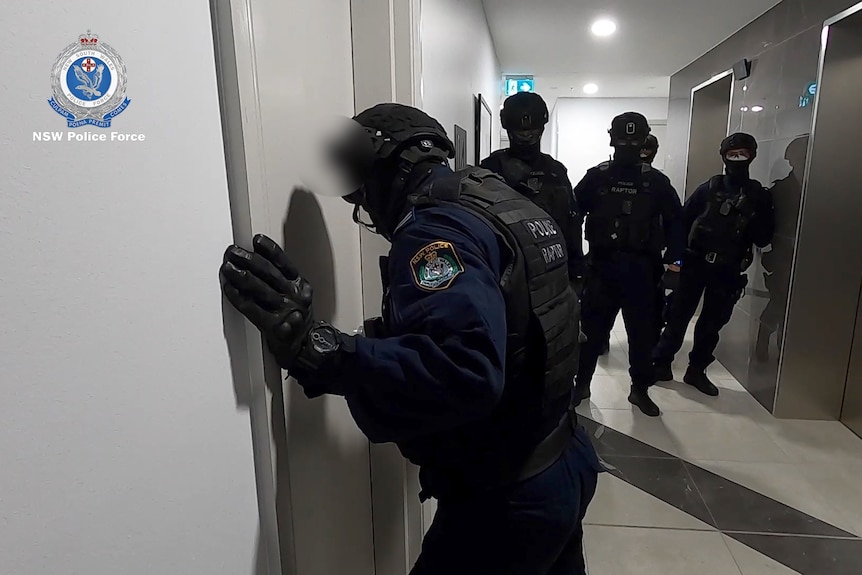 police dressed in riot gear at the front of a door