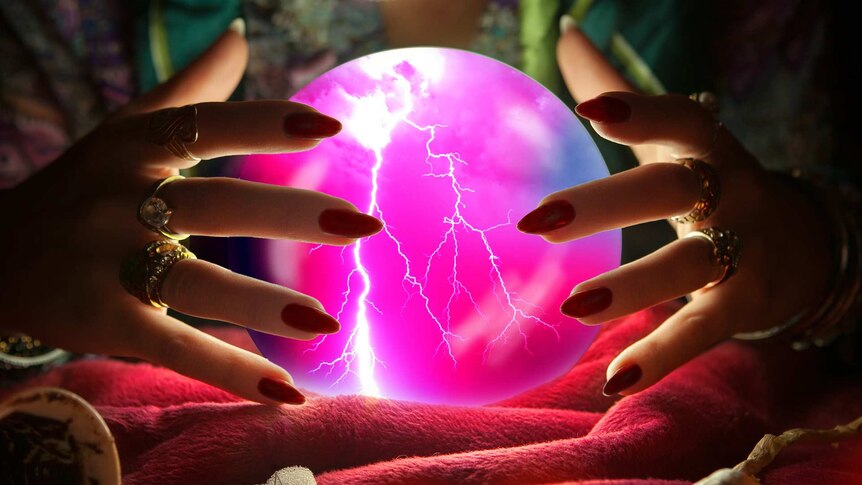 Two hands covered in jewellery and with painted nails hover over a crystal ball which shows a thunderstorm.