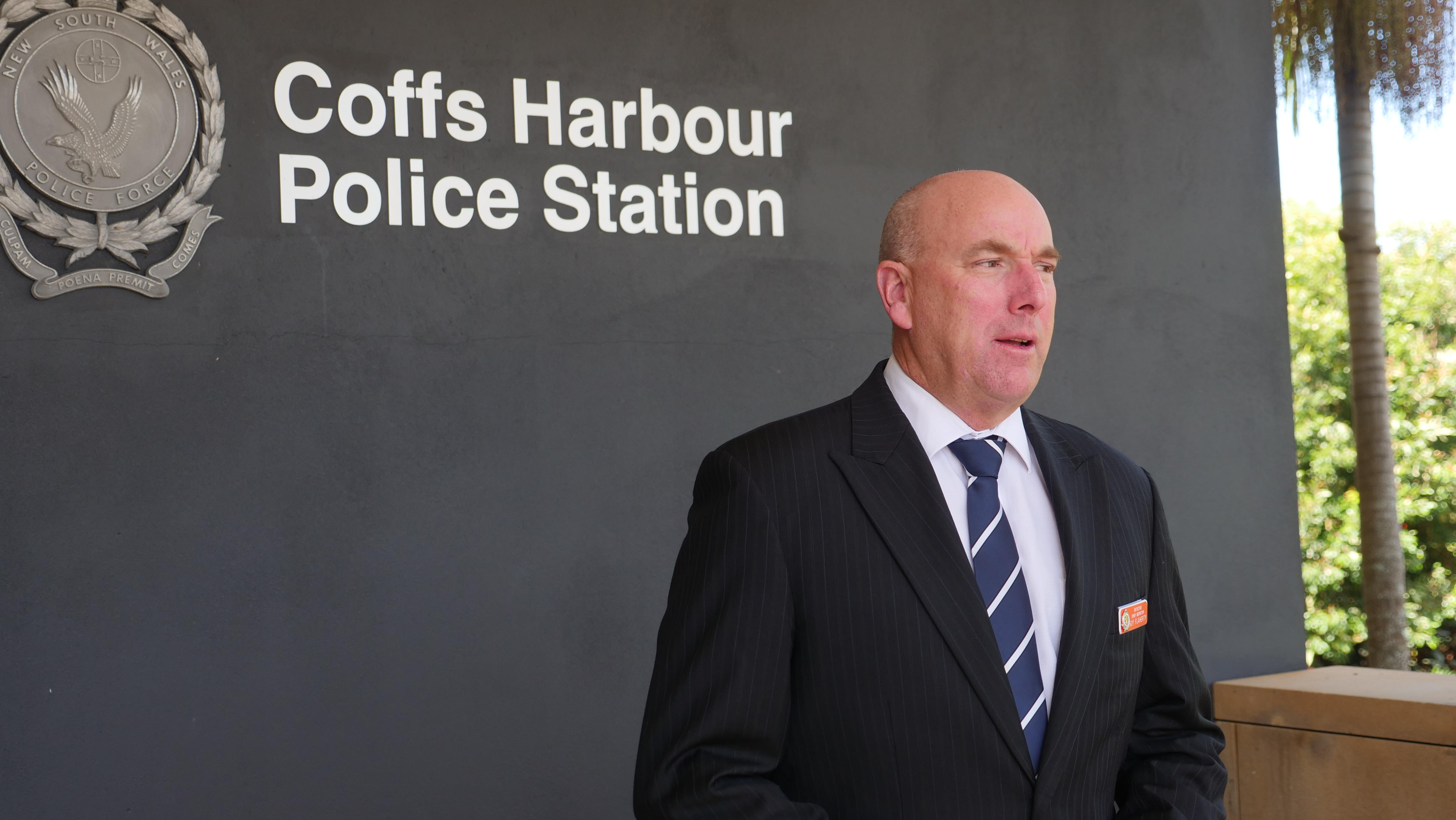 A man wearing a suit, in front of a police station.