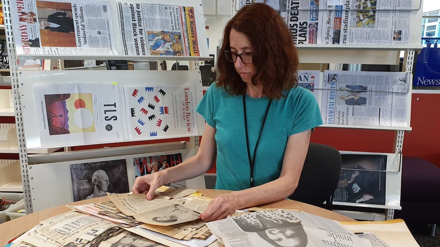 Librarian Keryn Kelleway looking at newspaper clippings spread on table about the Whitlam dismissal.