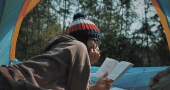 Camper reading book inside tent.