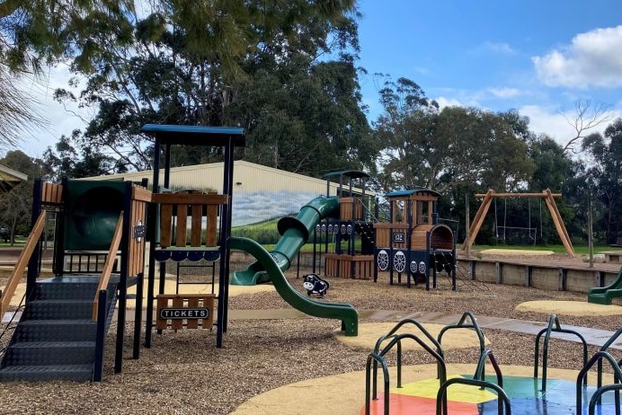 A playground with slides and swings with trees in the background