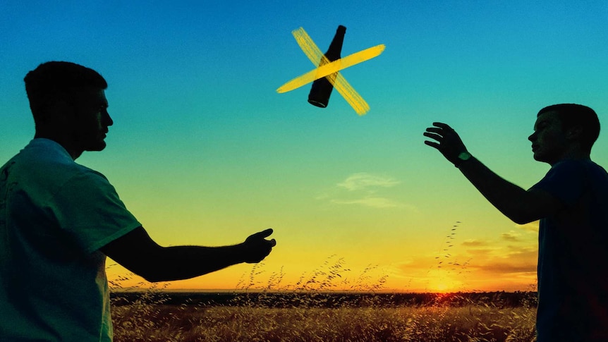 Two men on a field at sunset throwing a crossed-out beer to one another.