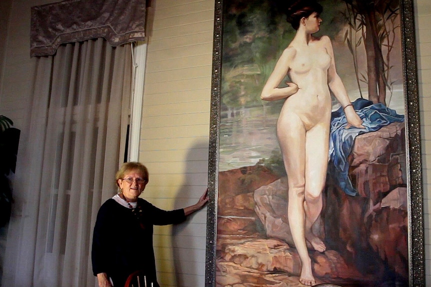 Elaine Madill stands next to a three-metre high painting of a naked woman.