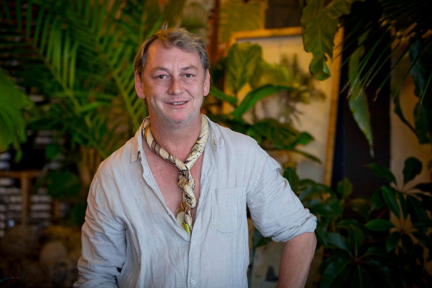 Mr Gray stands in his shop surrounded by indoor plants.