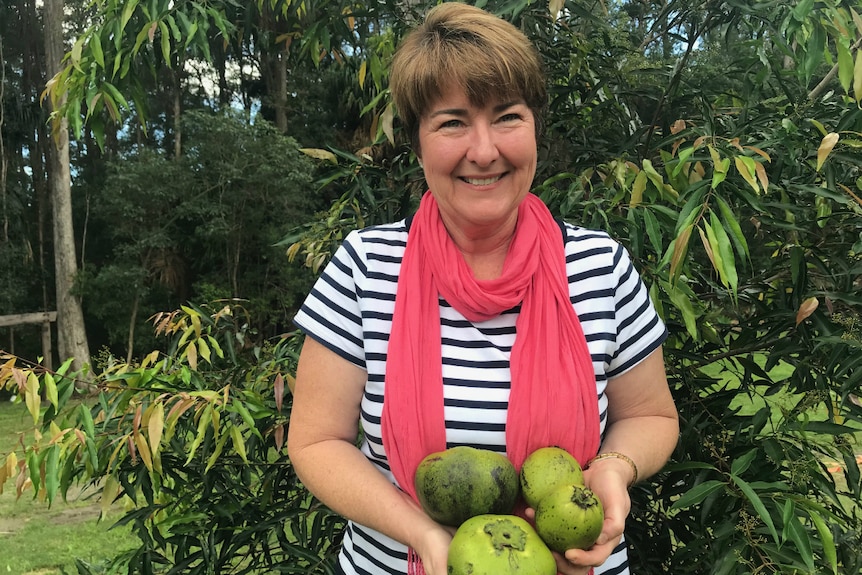 Helen Andrew holding black sapote fruit that Spare Harvest helped sell.