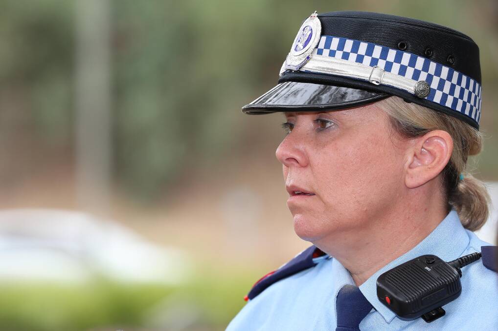 a woman from a side angle looking in the distance, with full blue police uniform attire