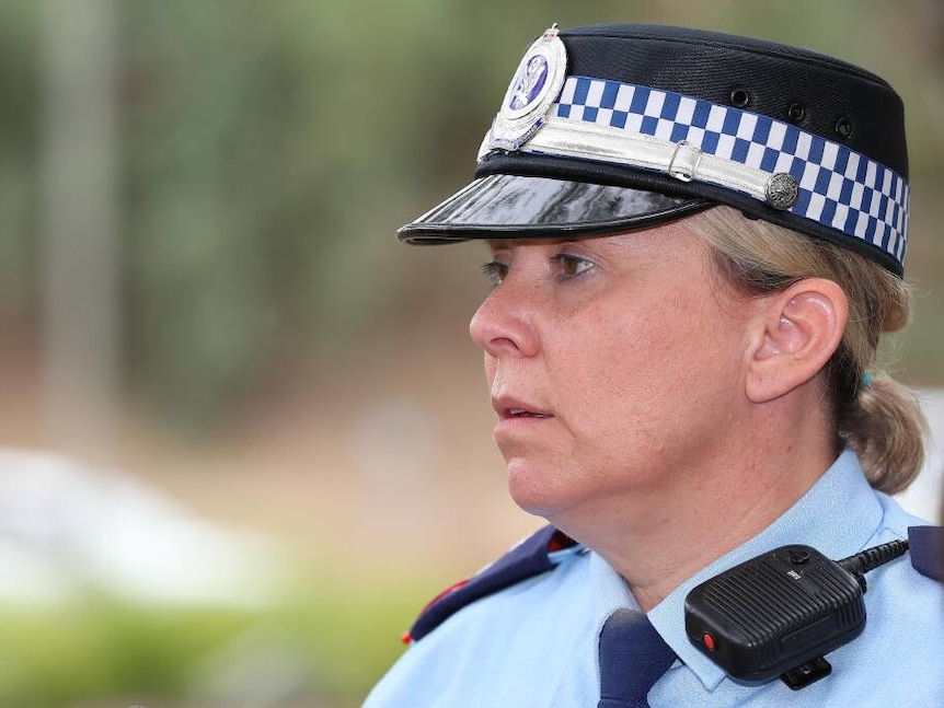 a woman from a side angle looking in the distance, with full blue police uniform attire