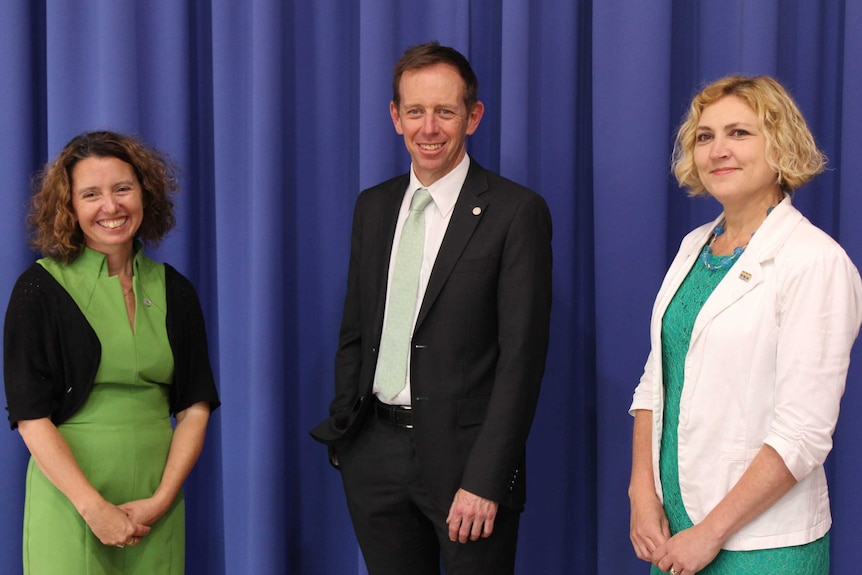 Two women and a man smile at the camera.