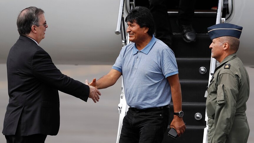Mexican Foreign Minister Marcelo Ebrard shacking hands with Evo Morales in front of a plane.