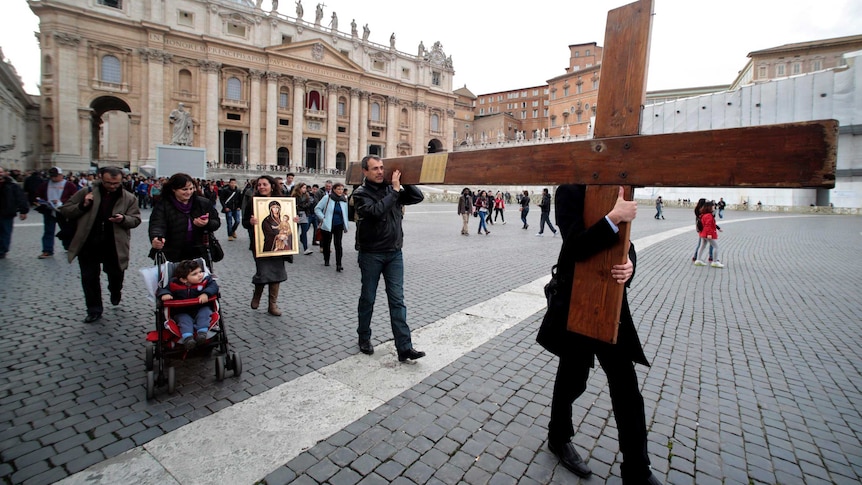 Pilgrims carry a cross at the Vatican.