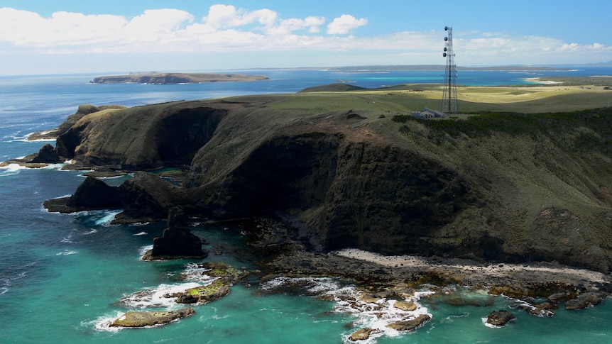View of an air monitoring station on a cliff top above an ocean coastline.