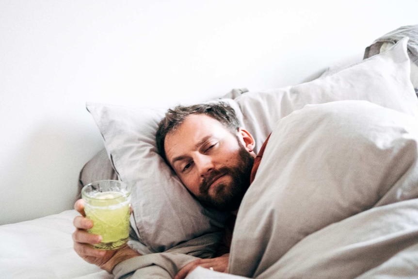 Man in bed looking sick.