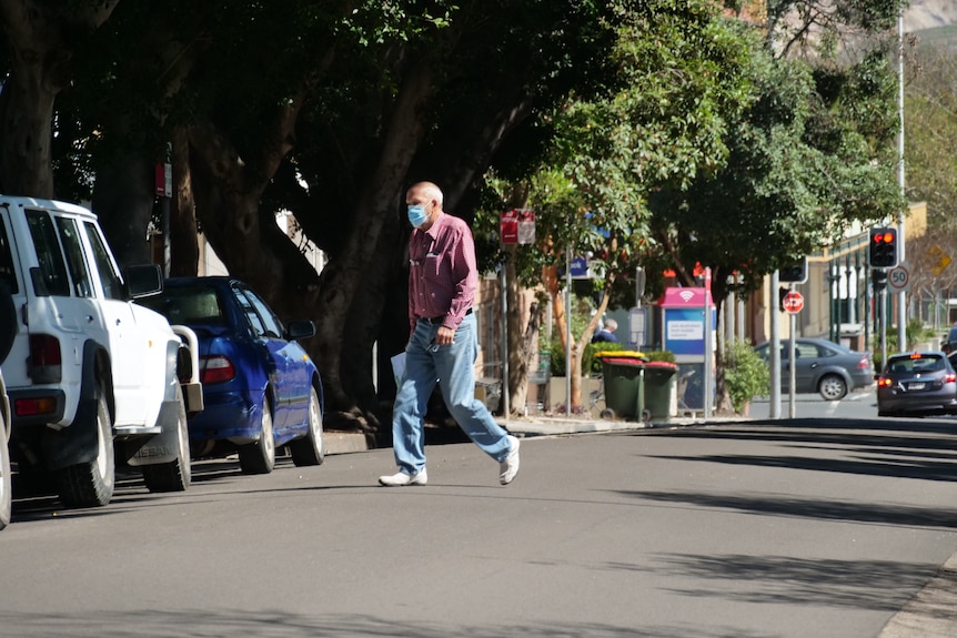 A man wearing a mask crossing the road