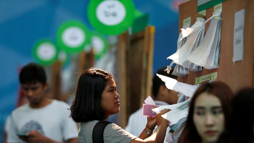 A woman looks at the candidate list ahead of the Thai election.