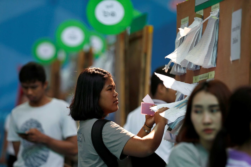 A woman looks at the candidate list ahead of the Thai election.