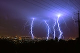 Four forks of lightning strike a city at night.