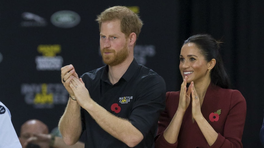 Prince Harry and Meghan in front of a crowd at a basketball game