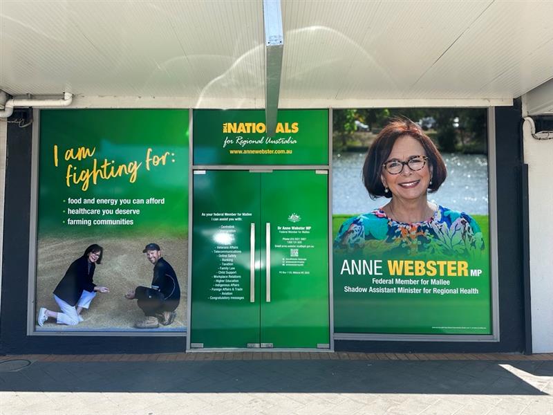 A shop-front window and double doors are covered in political advertising.