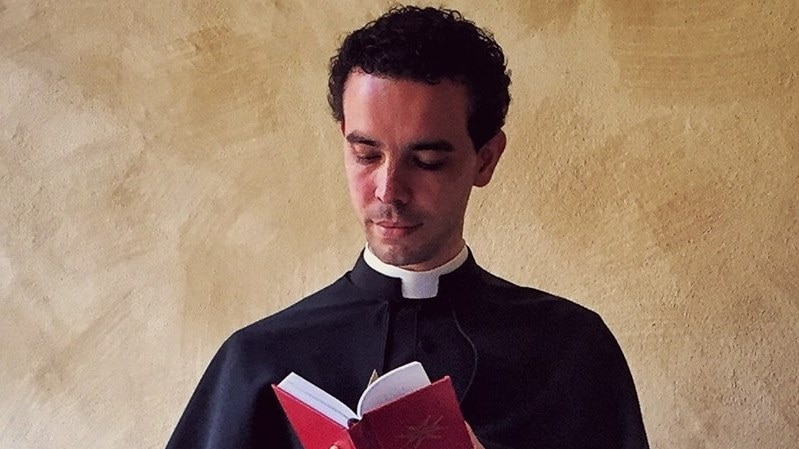 A man in priest's robes looks at a book