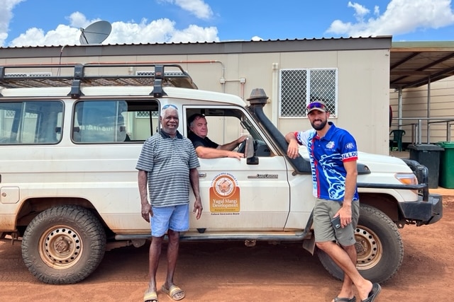 three men stand next to a car in the remote community of Ngukurr