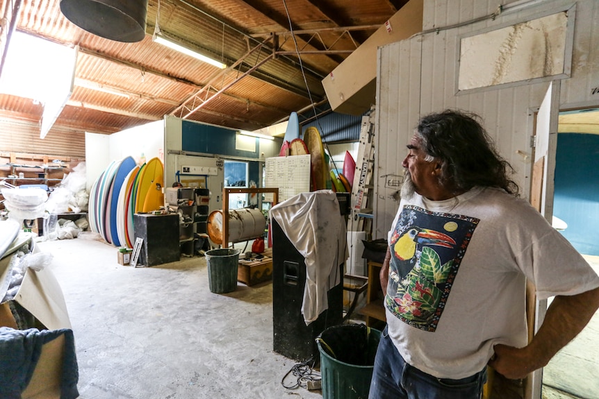 A man overlooks his surfboard workshop that once used to house chickens.
