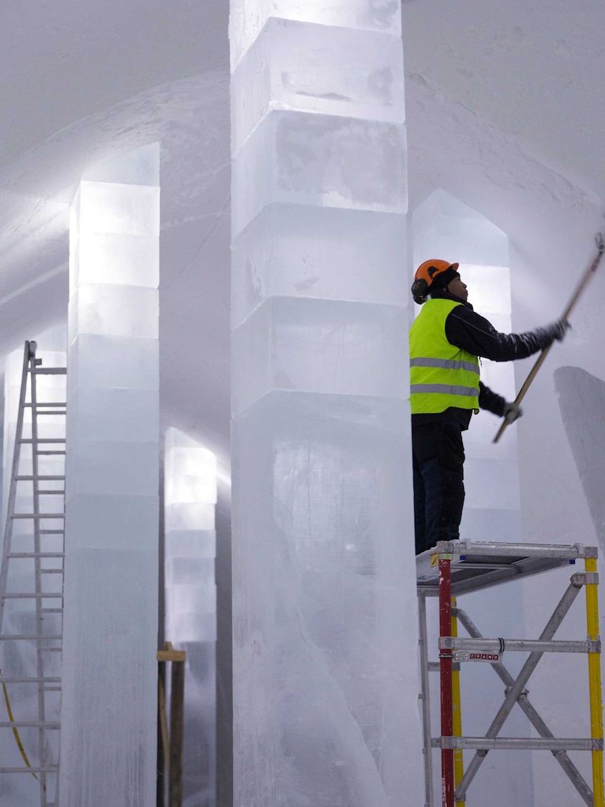 A support worker smooths icy walls inside the ice hotel.