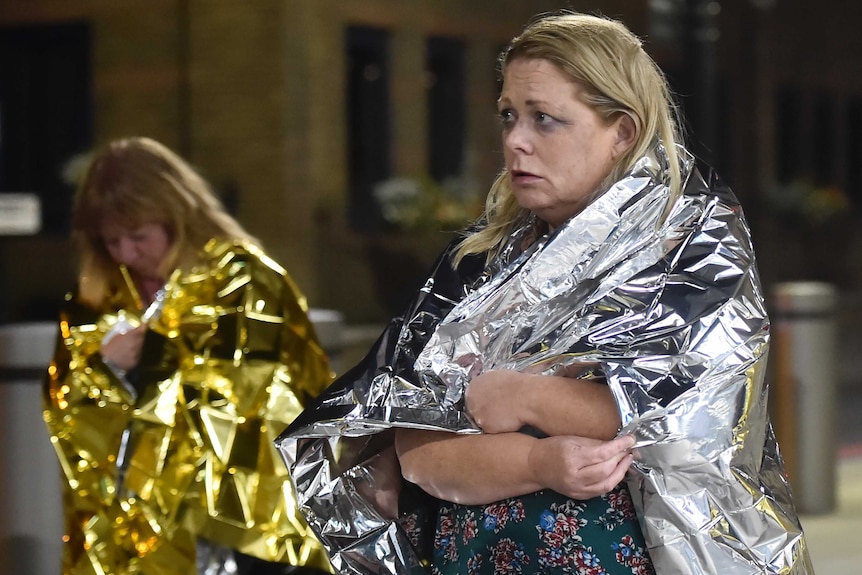 People leave the area wearing foil blankets.